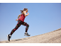 Mulher em roupa desportiva a correr numa subida, com leggings e top desportivo.