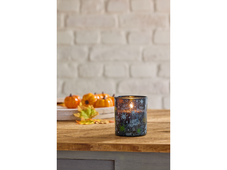 Vela de Halloween com aranhas e teias, abóboras decorativas e folhas de outono.