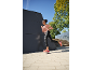 Mulher em roupa desportiva rosa e preta, a correr ao ar livre num passeio ensolarado.