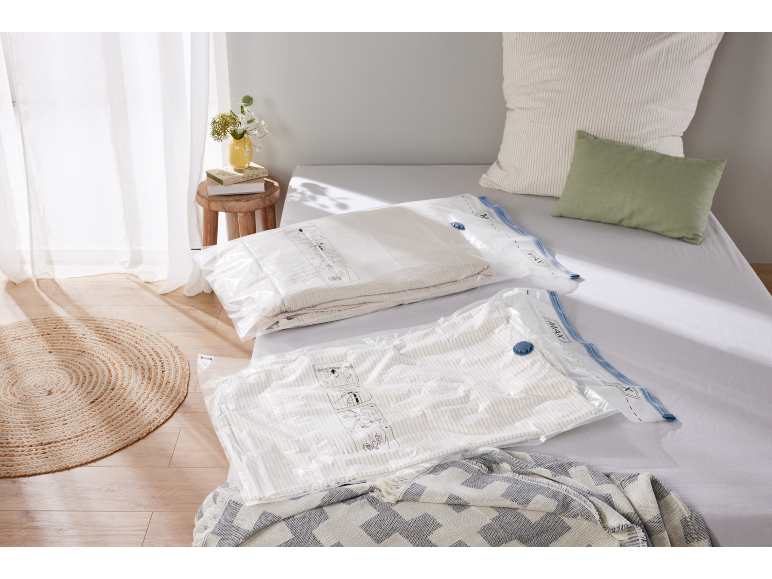 Sacos de armazenamento a vácuo com roupa de cama numa cama num quarto luminoso.