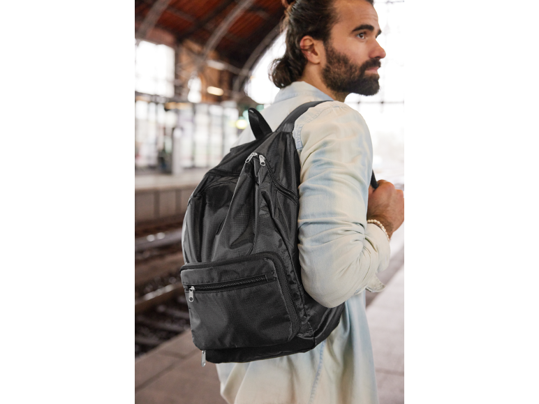 Homem com mochila numa estação de comboios.