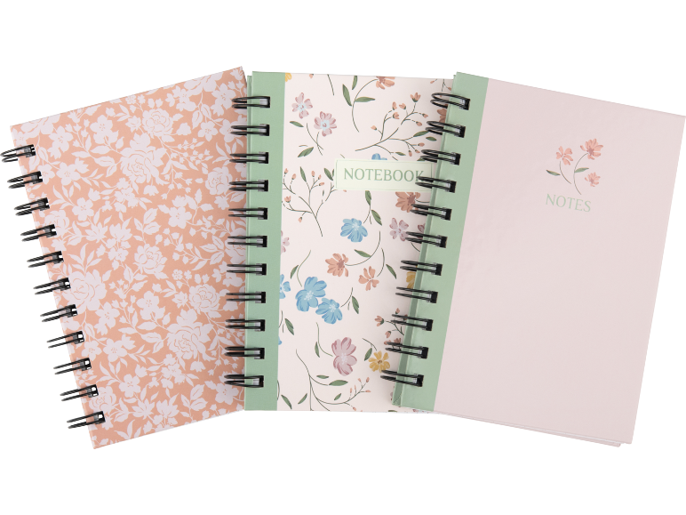 Três cadernos de argolas com padrões florais, um com 'NOTEBOOK' e outro com 'NOTES'.