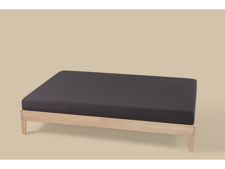 Estrutura de cama de madeira com um colchão cinzento escuro sobre um fundo claro.