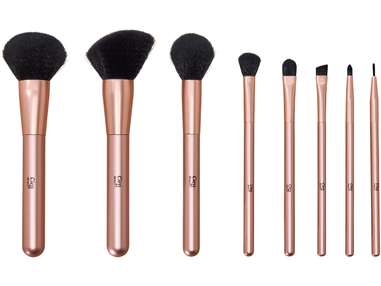 Conjunto de oito pincéis de maquilhagem em ouro rosa, incluindo pincéis para pó, blush e olhos.