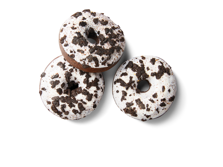 Três donuts de chocolate com cobertura branca e pedaços de bolacha.