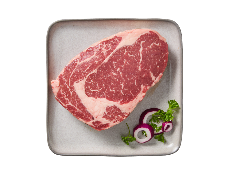 Bife de entrecôte cru num prato, guarnecido com cebola roxa e salsa.