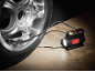 Inflador de pneus portátil com luz embutida conectado a um pneu de carro.