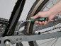 Uma mão usa uma chave de fenda flexível para ajustar uma bicicleta.