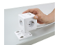 Mão segurando uma extensão cúbica branca com tomadas e portas USB, fixada a um suporte de mesa.