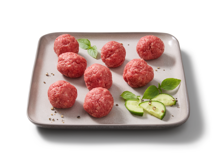 Almôndegas cruas e pepino numa travessa cinzenta.