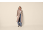 Mulher com gabardine, top às riscas, jeans e mocassins.