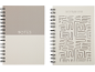 Dois cadernos em espiral, um com 'NOTES' numa capa de dois tons, o outro com 'NOTEBOOK' e um padrão de labirinto.