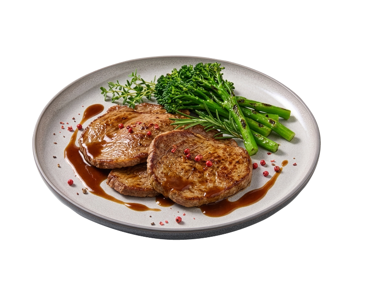 Medalhões de carne grelhados com brócolos e molho num prato.