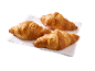 Três croissants dourados sobre um guardanapo branco, prontos para saborear.