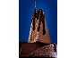 Bolo de chocolate com calda de chocolate derretida sobre fundo azul.
