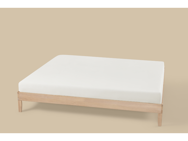 Cama de madeira com colchão branco sobre fundo bege.