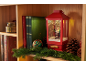 Decoração de Natal com lanterna vermelha com Pai Natal, livros e guirlanda numa prateleira de madeira.