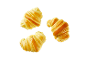 Três croissants dourados com um acabamento brilhante sobre um fundo preto.