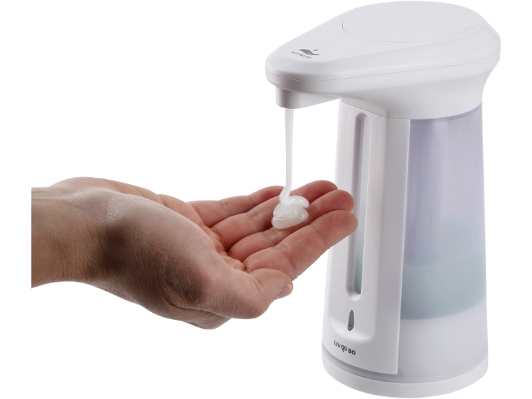 Dispensador automático de sabão branco a dispensar sabão numa mão.