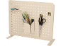 Painel perfurado bege com organizador de canetas, tesoura e fitas decorativas.