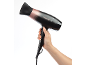 Secador de cabelo preto e ouro rosa segurado na mão em fundo branco.