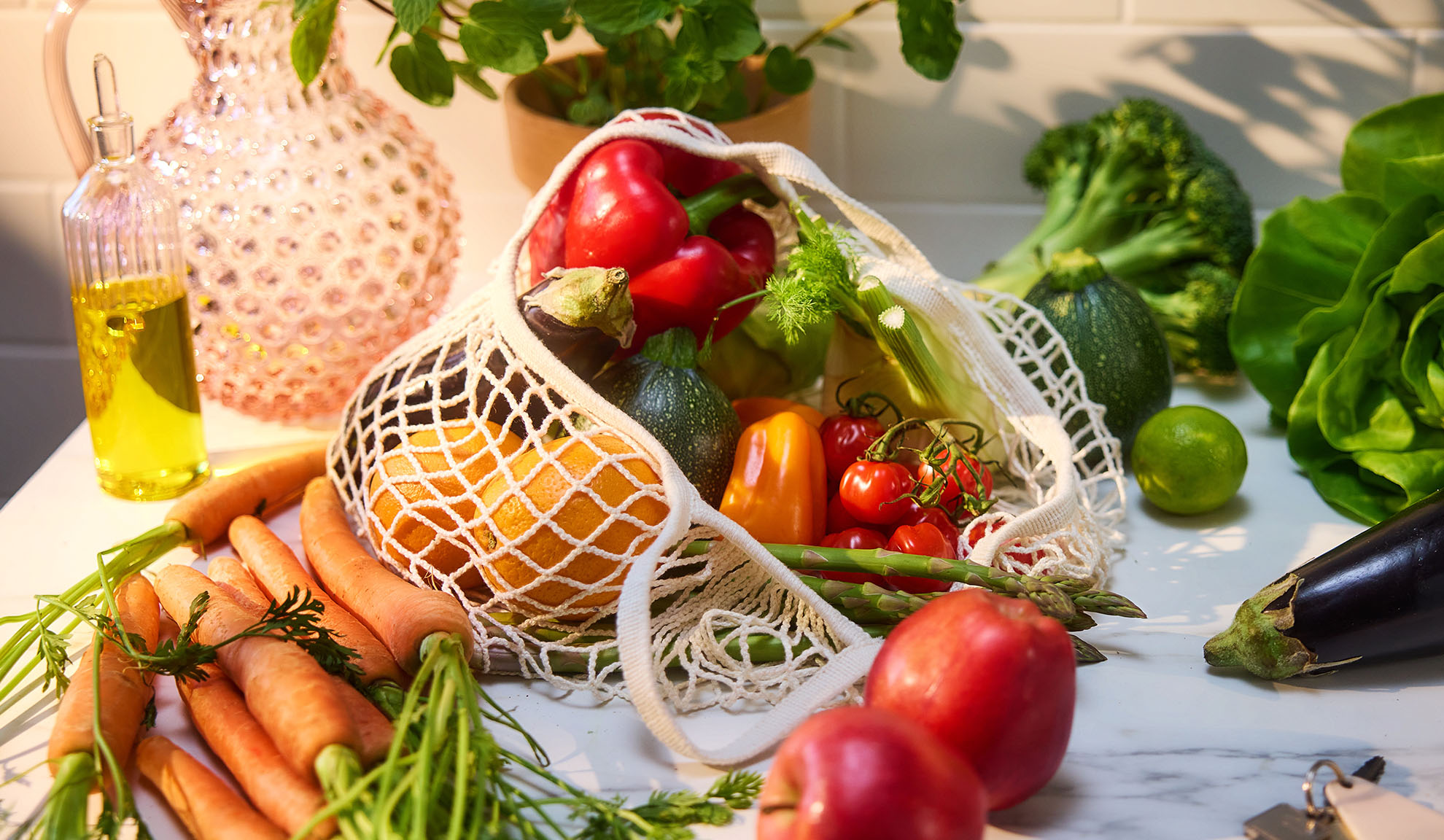 Vegetais e frutas frescas, como pimentões, laranjas e cenouras, num saco de compras.