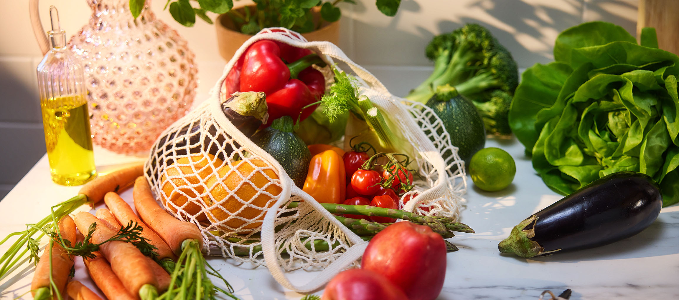 Vegetais e frutas frescas, incluindo cenouras, pimentões, tomates, alface e berinjela, sobre uma mesa.