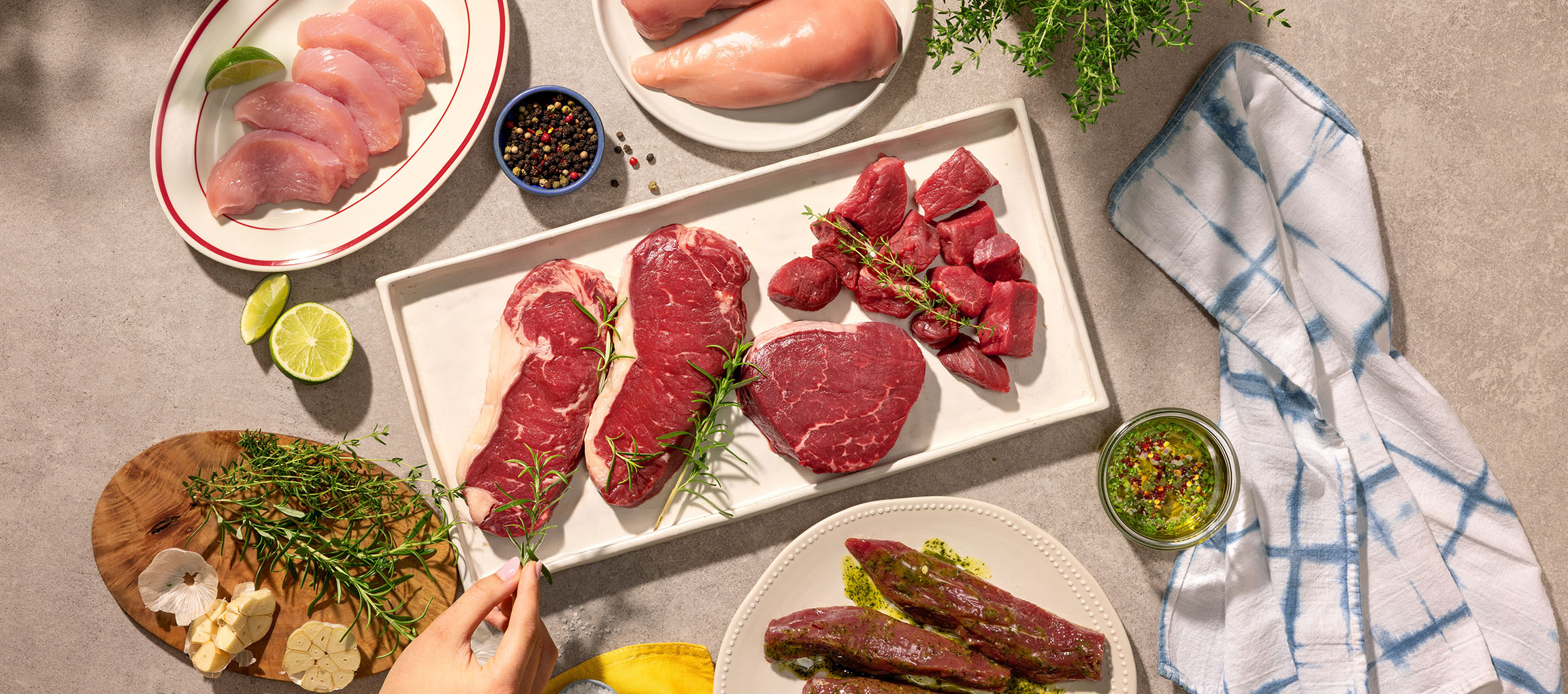 Vários cortes de carne crua, incluindo frango e carne bovina, com ervas e especiarias.