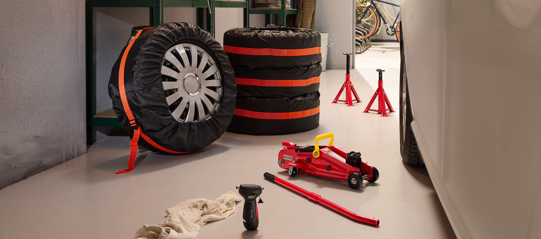 Pneus de carro com capas, macaco e cavaletes numa garagem.