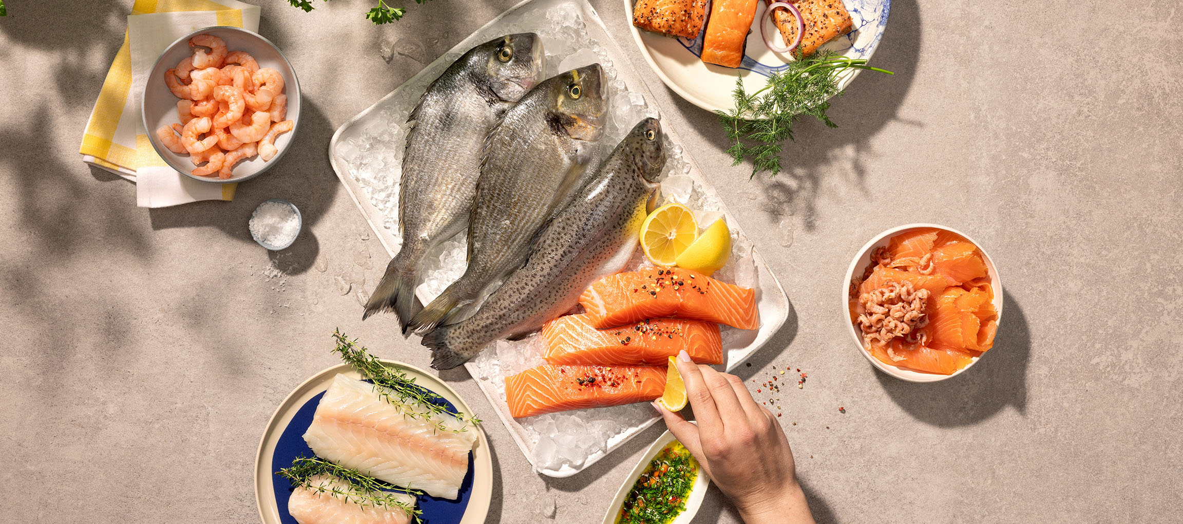 Variedade de marisco fresco, incluindo peixe inteiro, filetes de salmão e camarão, no gelo.