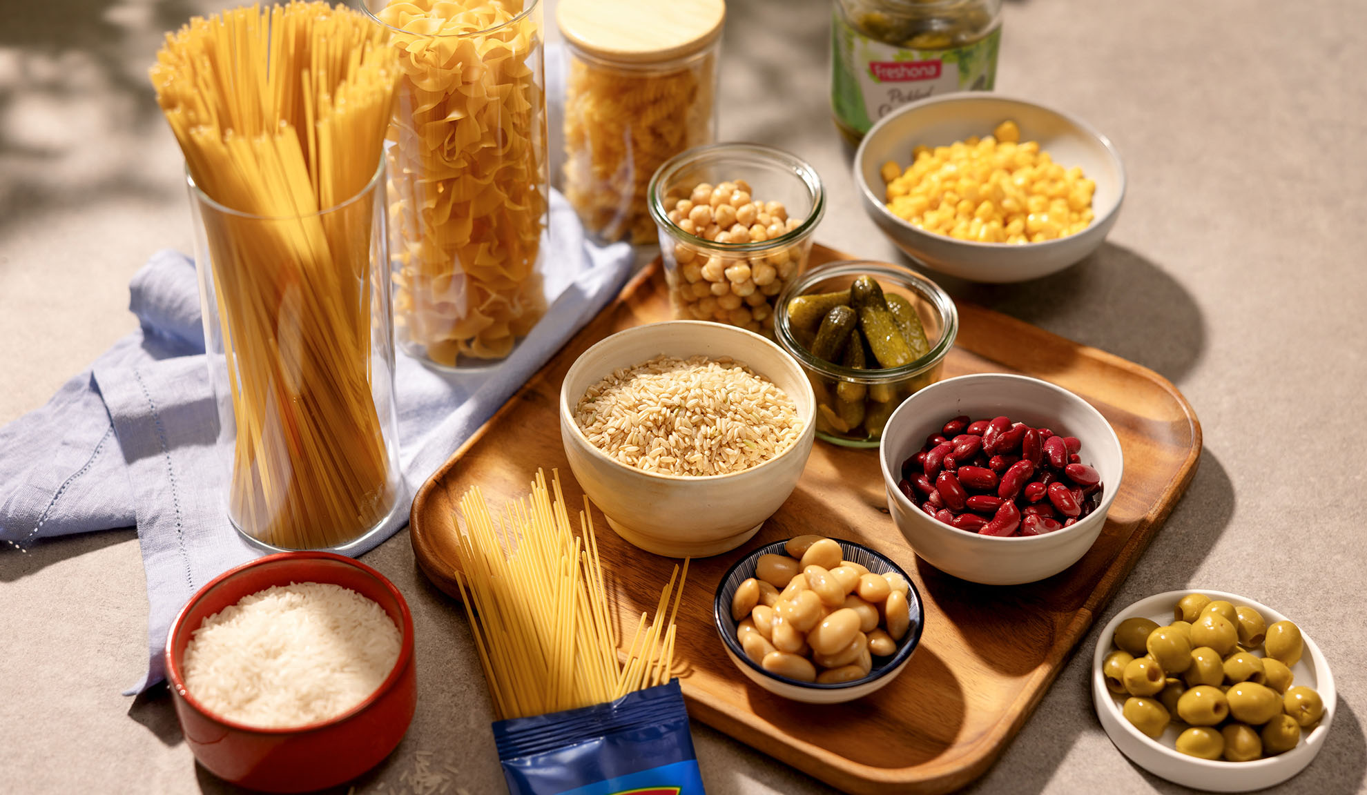 Variedade de massa seca, arroz, grão-de-bico, feijão, milho, picles e azeitonas.