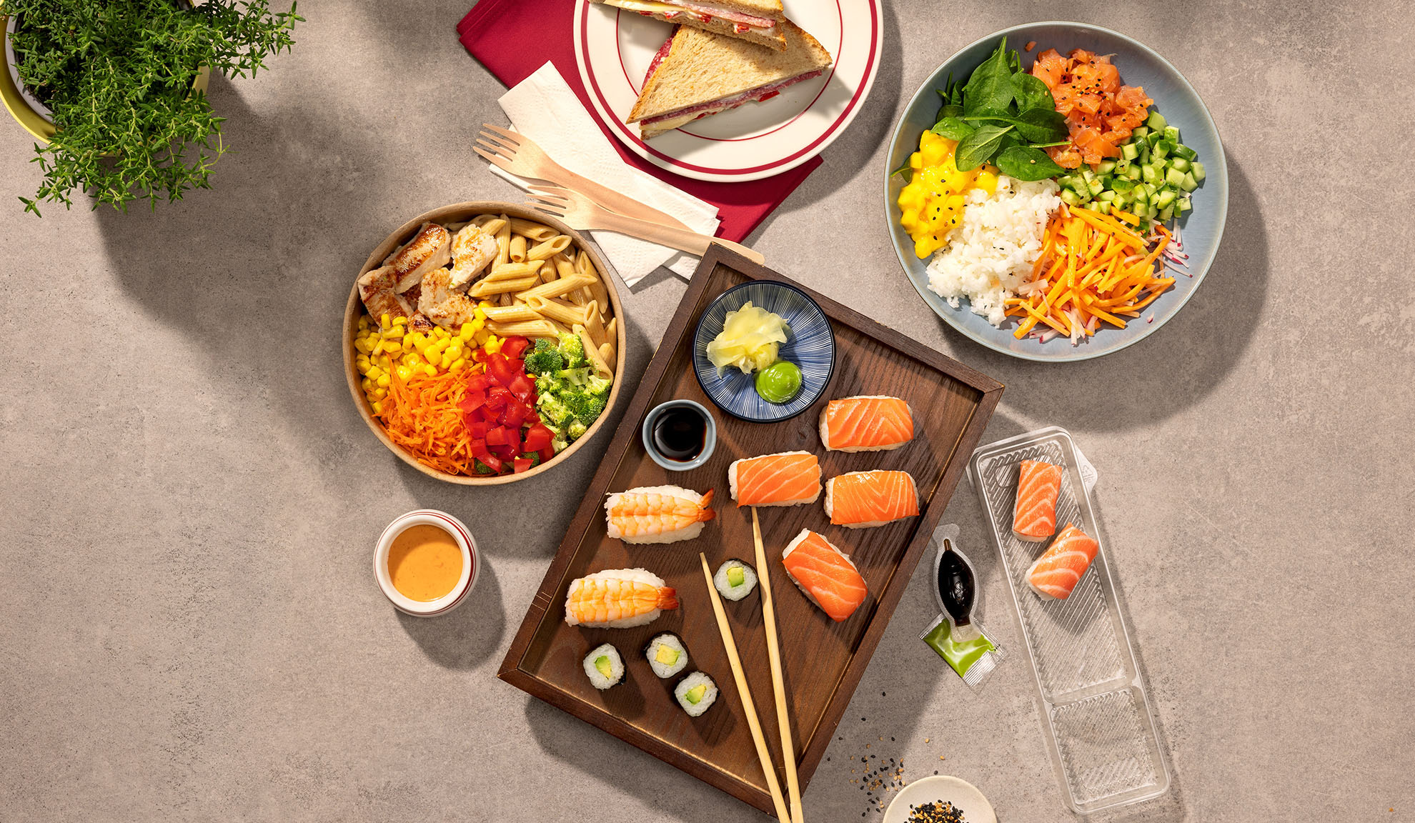 Vista aérea de várias refeições para levar: sushi, poke bowl, salada de massa e sanduíches.