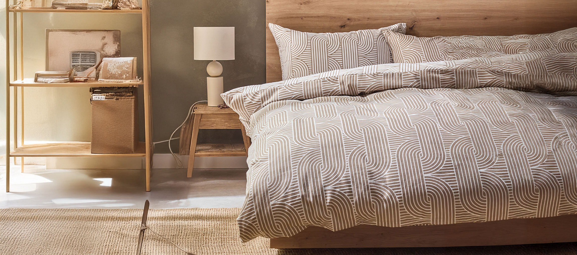 Quarto com cama de madeira, roupa de cama estampada, mesa de cabeceira e estante.