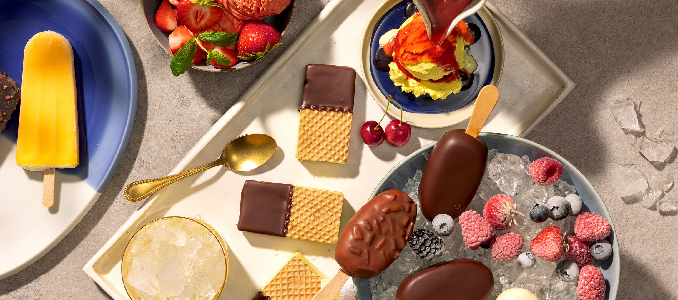 Variedade de gelados de pau, bolas de gelado e wafers cobertos de chocolate com frutos silvestres.