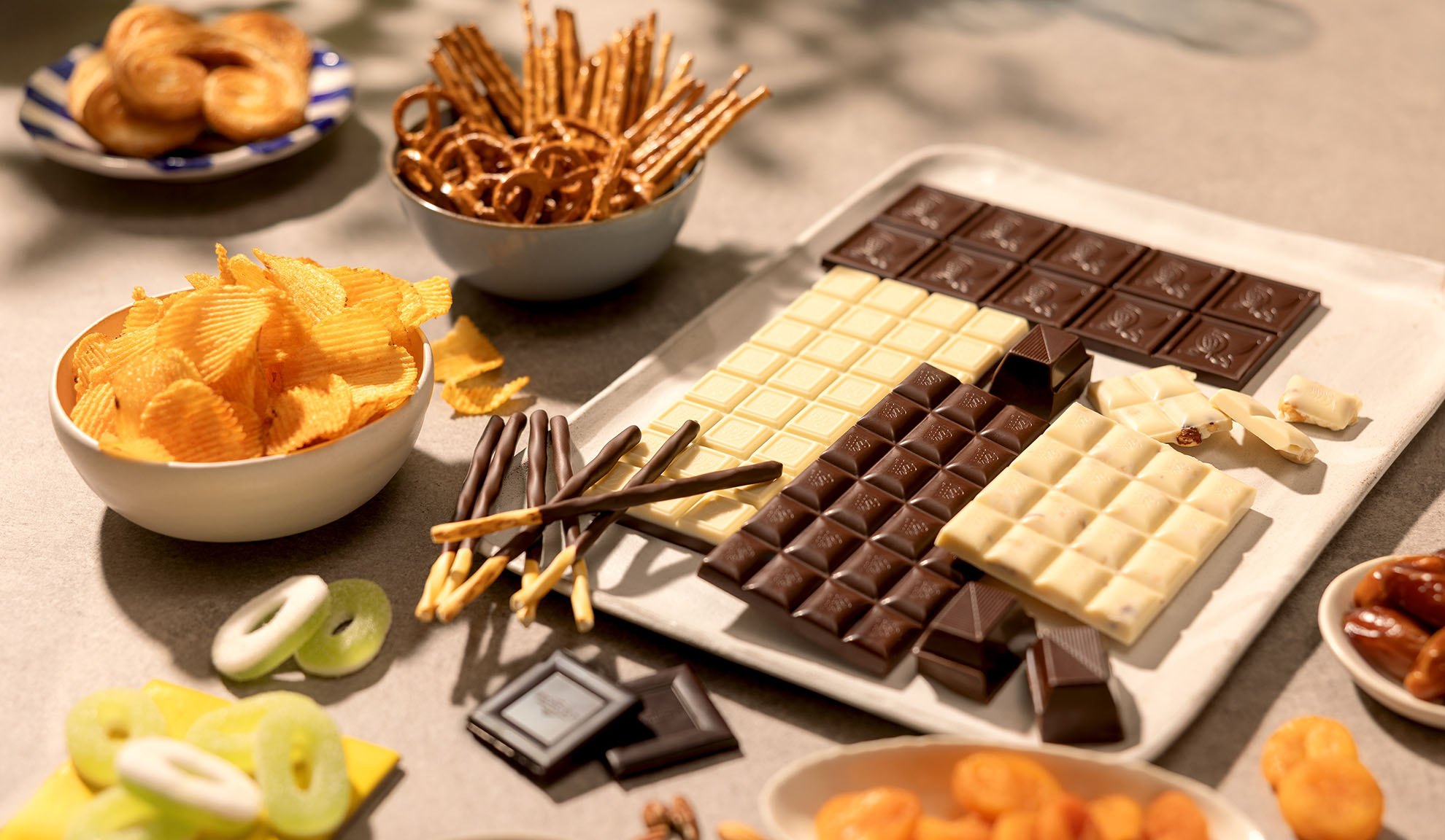 Uma variedade de snacks, incluindo barras de chocolate, batatas fritas, pretzels e doces.