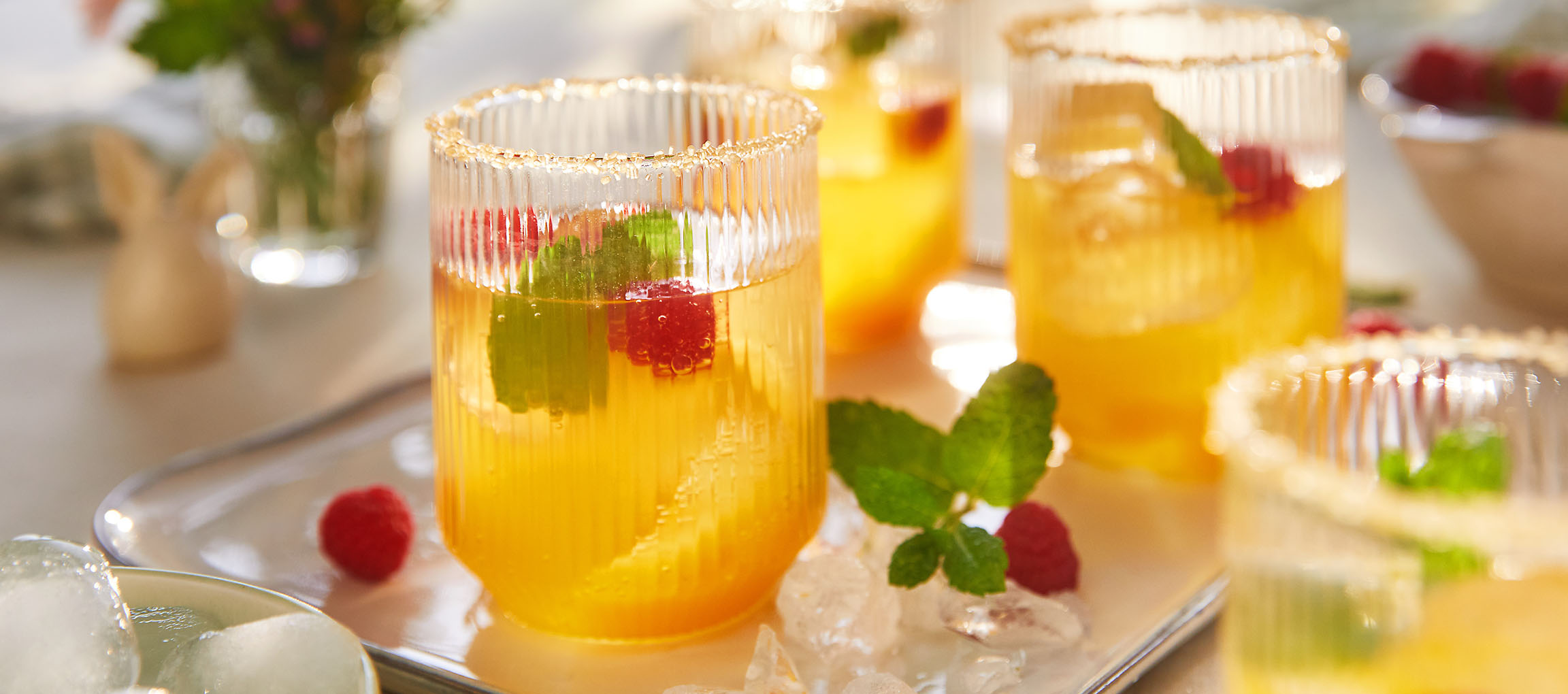 Copos de bebida refrescante com framboesas e hortelã, servidos numa bandeja.