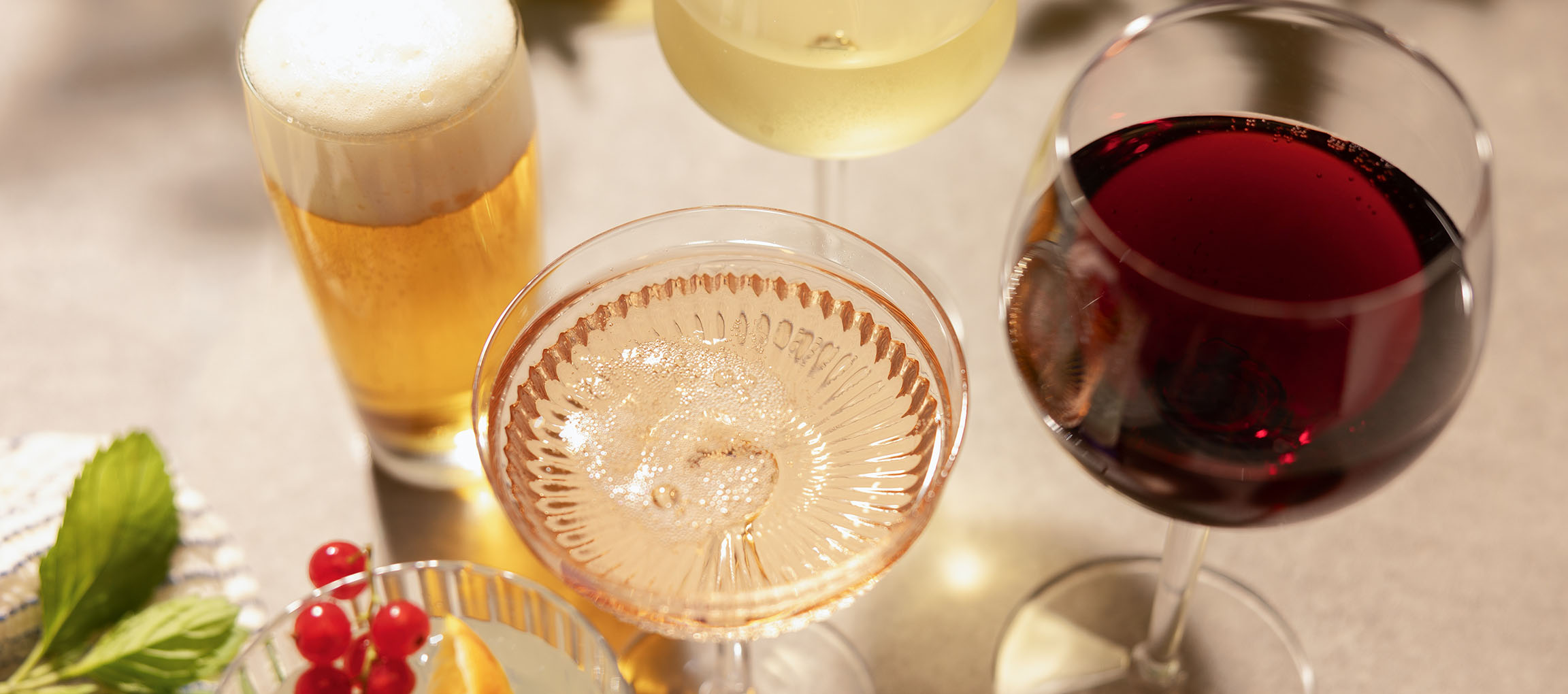 Cerveja, vinho rosé e vinho tinto em copos, com bagas e hortelã.