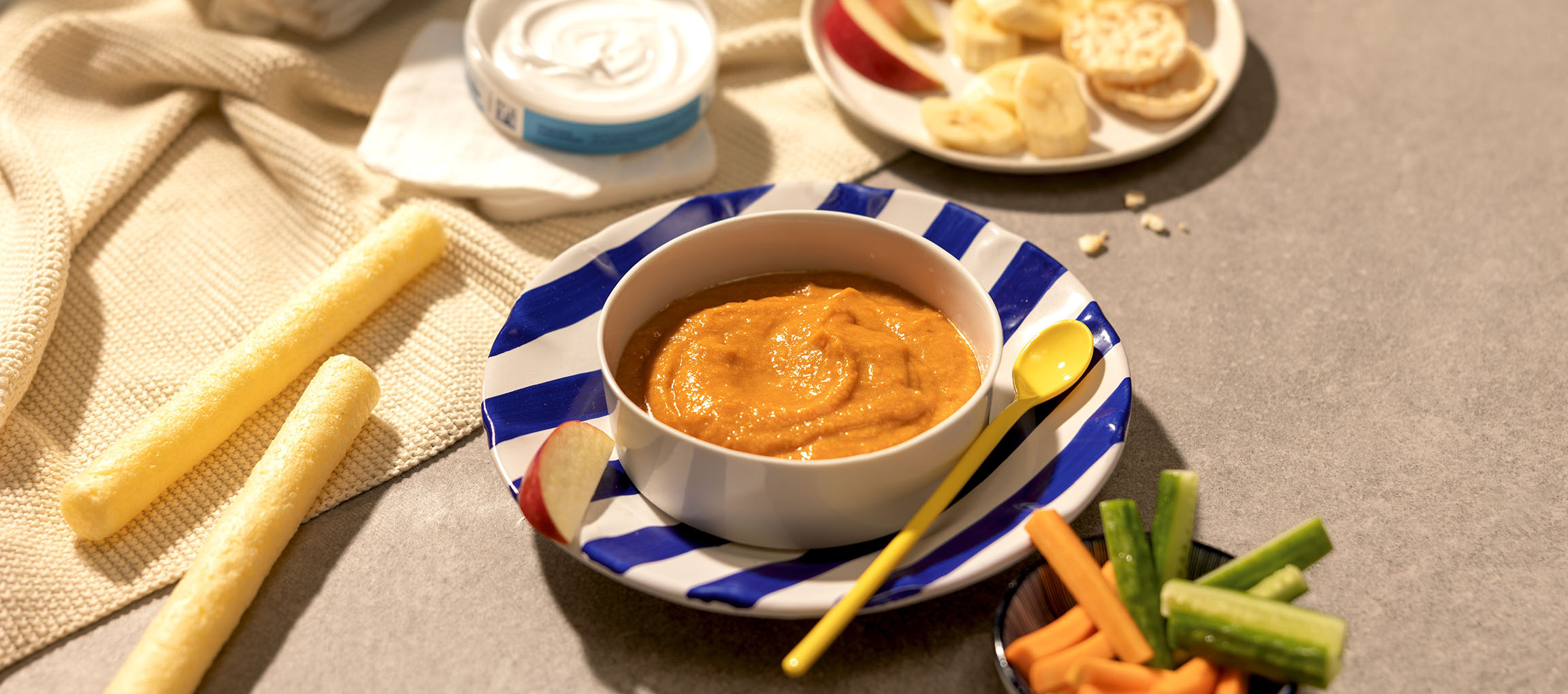 Puré de comida para bebé com snacks como fruta, bolachas e palitos de vegetais.