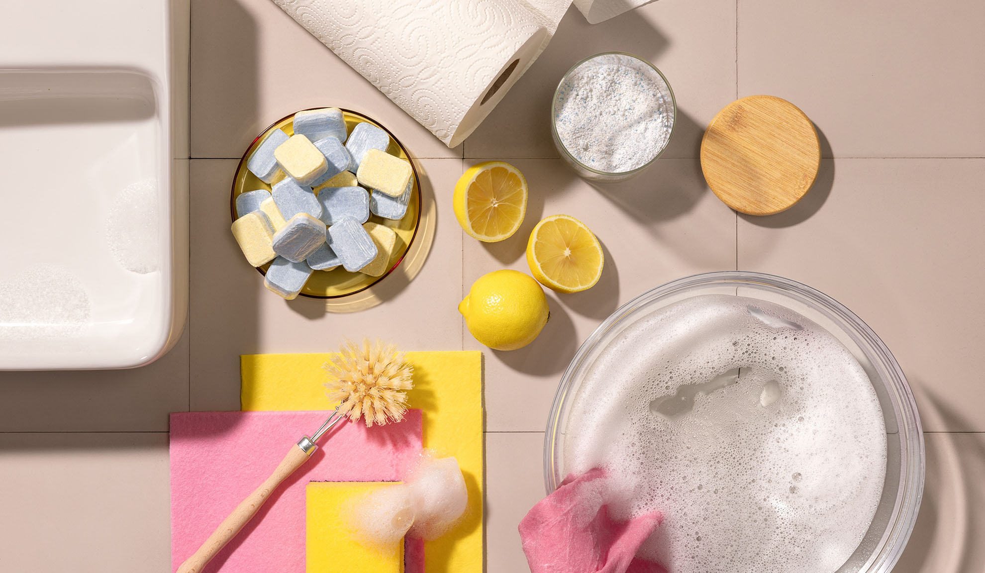 Produtos de limpeza: pastilhas para máquina de lavar loiça, limões, pó e esponjas.