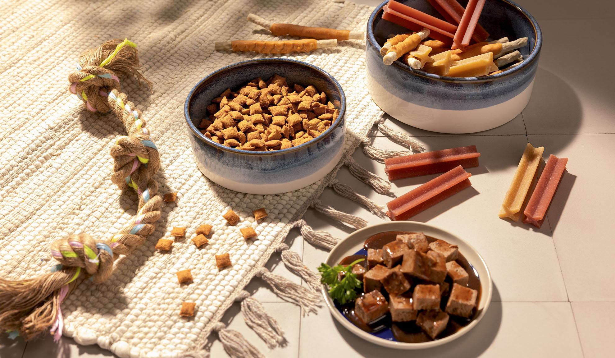 Variedade de comida e guloseimas para animais de estimação, incluindo ração seca, comida húmida e snacks para mastigar.