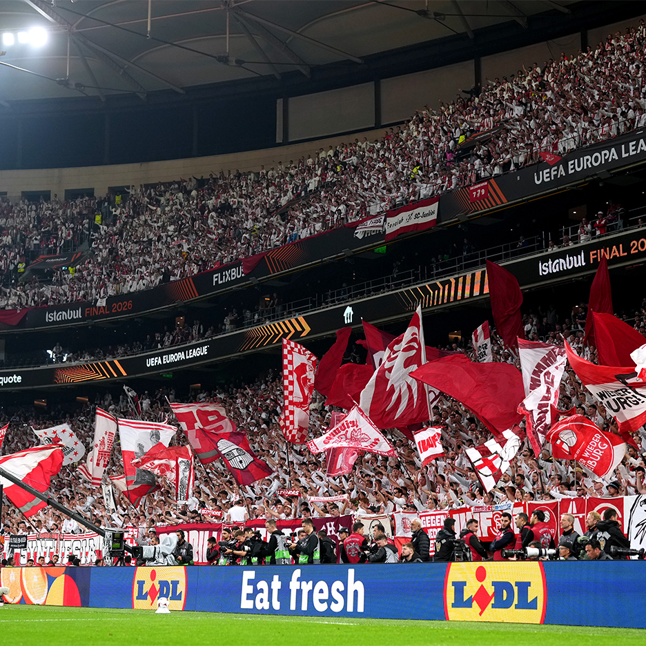 Nogometni navijači na stadionu sa zastavama, ispod se nalazi Lidl reklama za "Eat fresh".