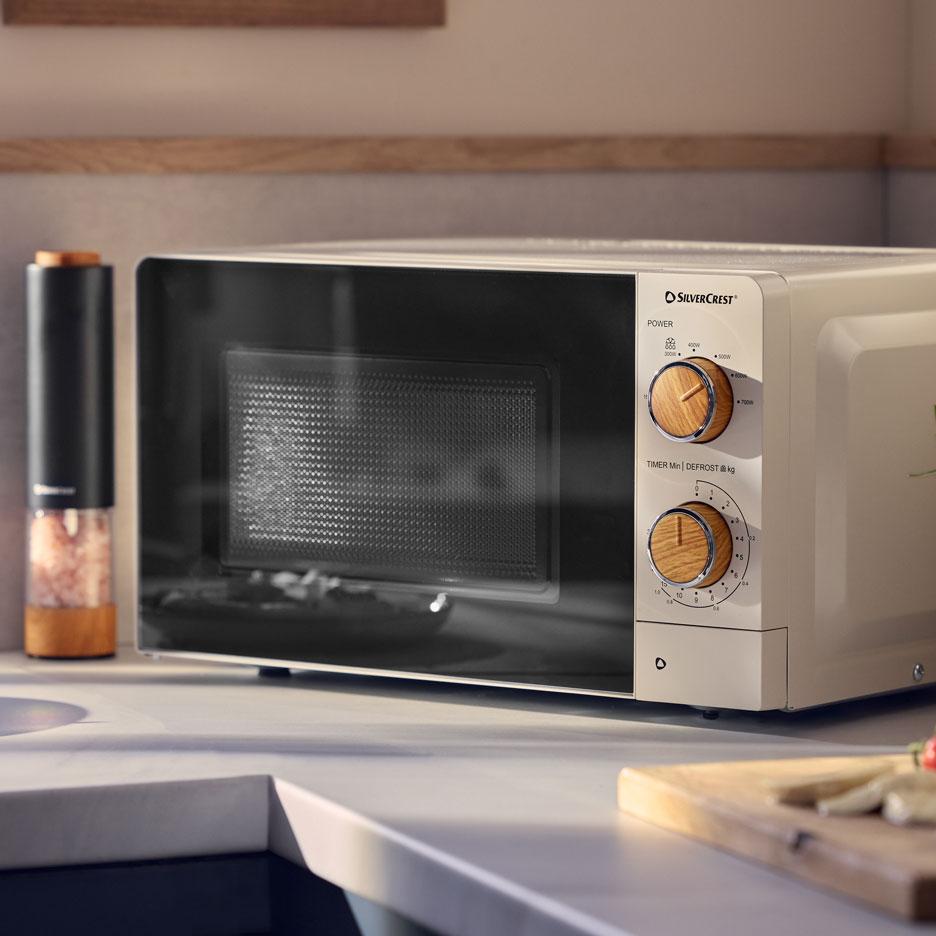 Micro-ondas creme com botões de madeira numa bancada de cozinha.
