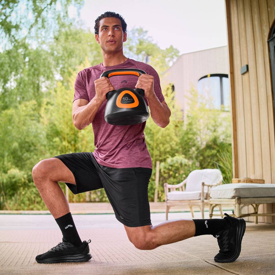 Homem a fazer lunges com um kettlebell de 10 kg ao ar livre.