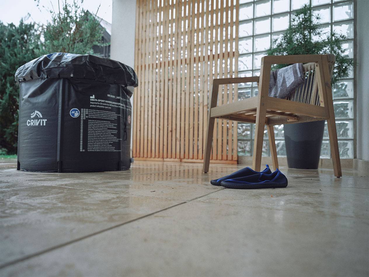 Piscina insuflável Crivit e sapatos de água num pátio.