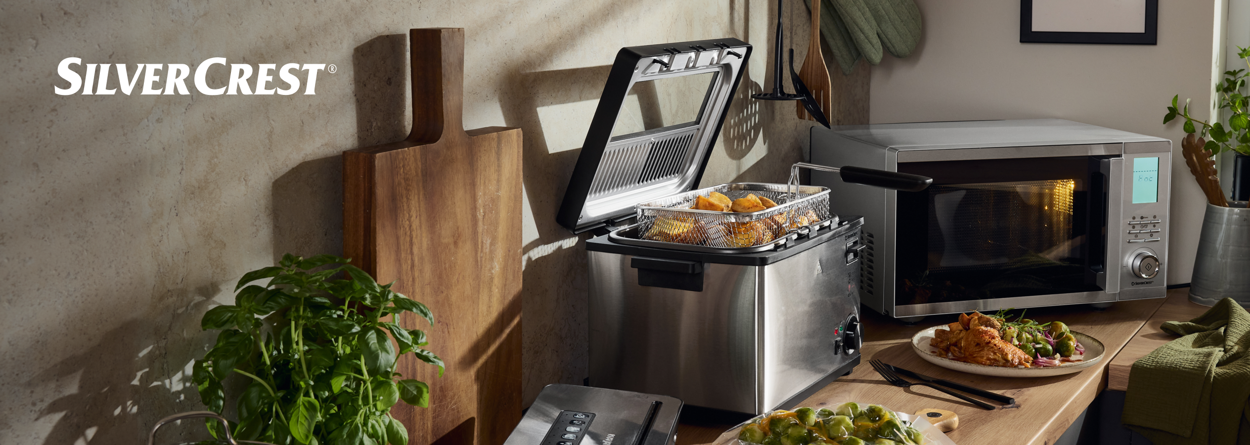 Fritadeira SilverCrest e micro-ondas numa cozinha moderna com comida.