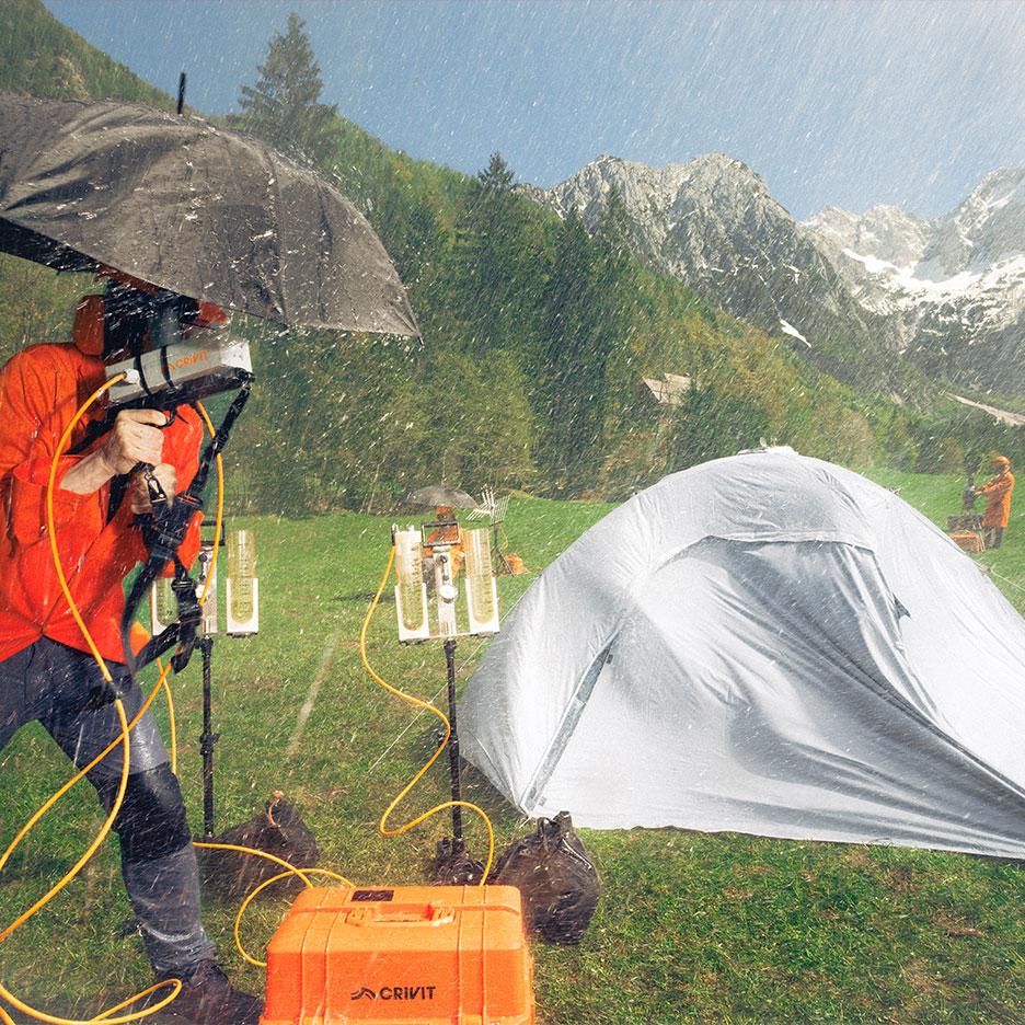 Pessoa com equipamento de chuva testando equipamento de campismo à chuva com montanhas.