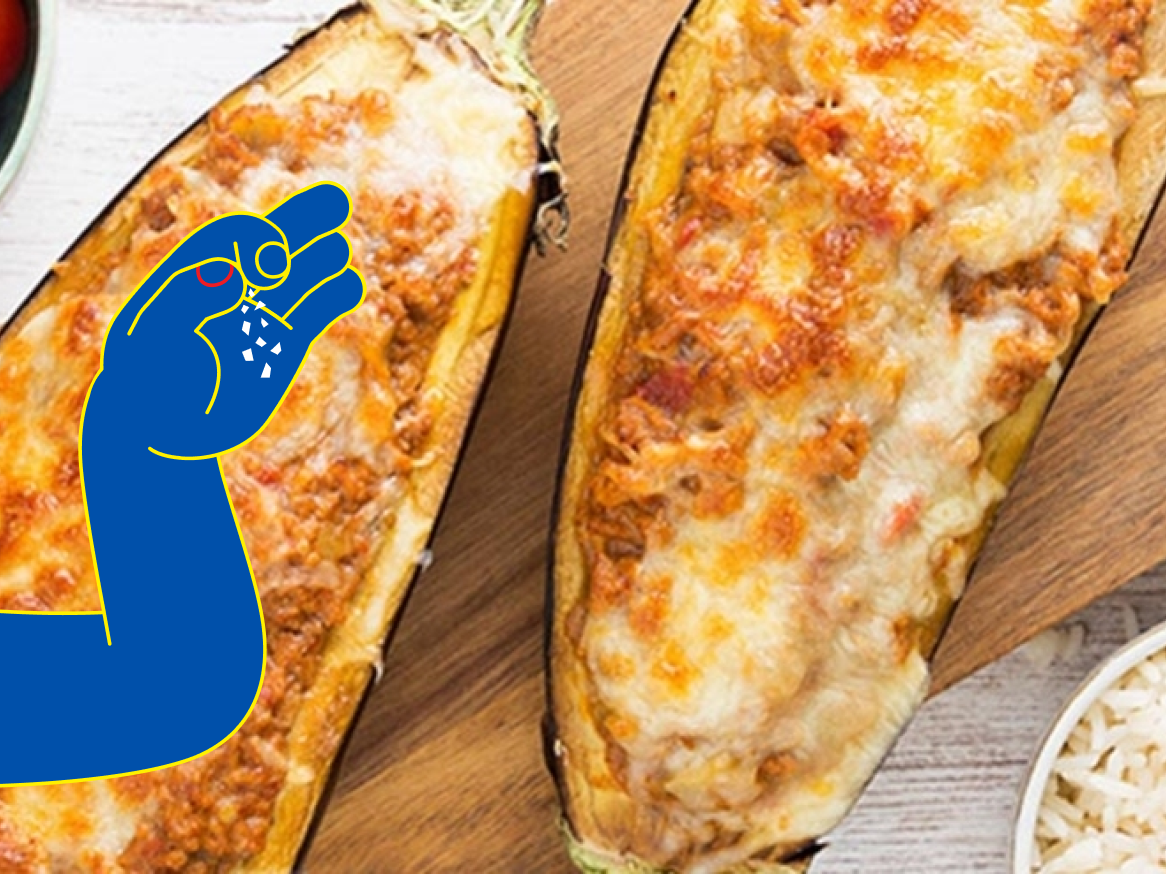 Beringelas recheadas com carne picada e queijo gratinado, com uma mão a polvilhar sal.