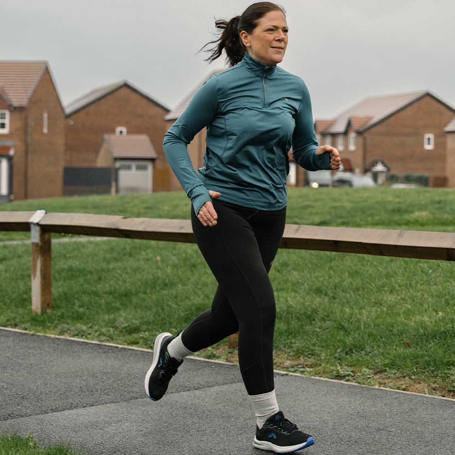 Mulher em roupa desportiva a correr num caminho ao ar livre.