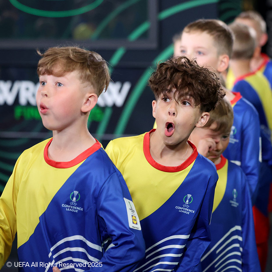 Dois meninos com camisolas amarelas e azuis com motivos de futebol, parecem surpresos.