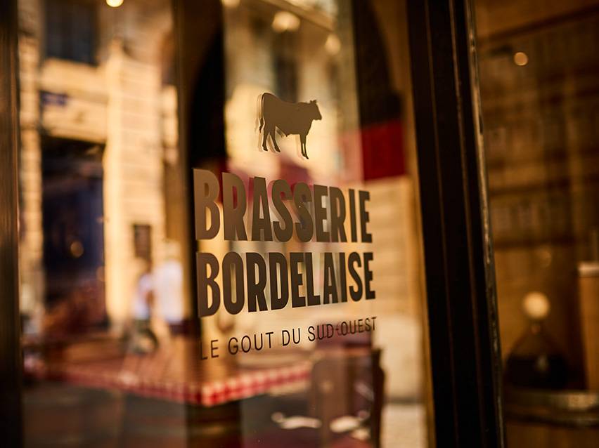 Letreiro da Brasserie Bordelaise com silhueta de vaca e o texto 'Le Goût du Sud-Ouest'.